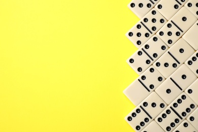 Classic domino tiles on yellow background, flat lay. Space for text