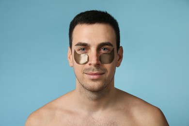Photo of Young man with under eye patches on light blue background