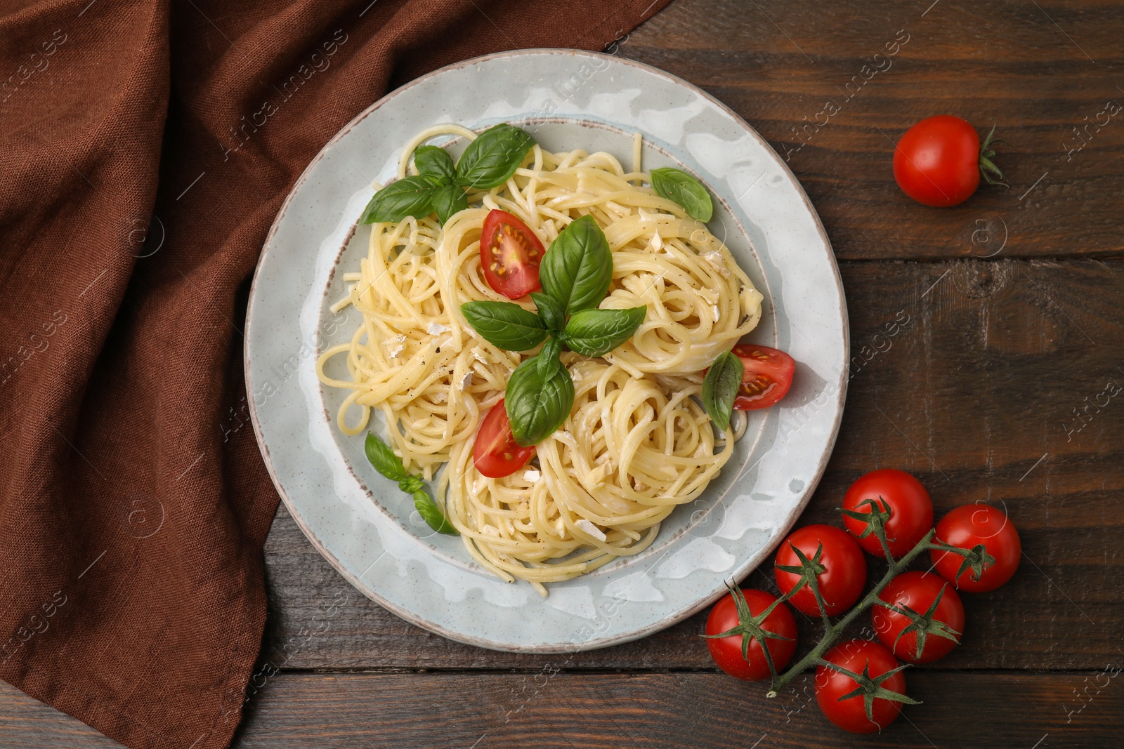 Photo of Delicious pasta with brie cheese, tomatoes and basil leaves on wooden table, flat lay