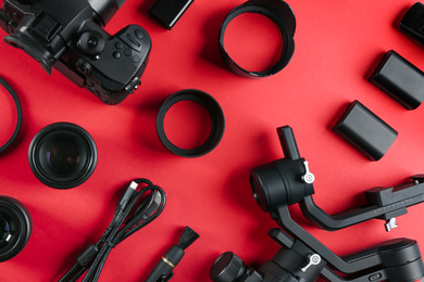 Flat lay composition with camera and video production equipment on red background
