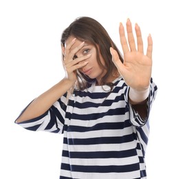 Embarrassed woman covering face with hand on white background