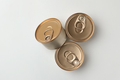 Photo of Tin cans with wet cat food on white background, top view
