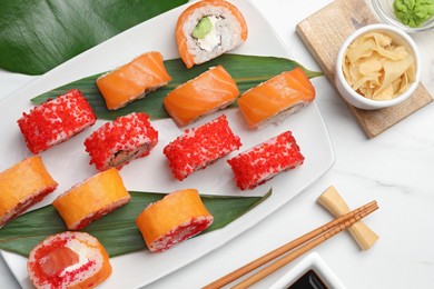 Flat lay composition with delicious sushi rolls on white marble table