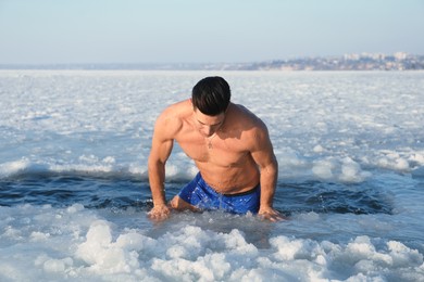 Photo of Man getting out of ice hole on winter day. Baptism ritual