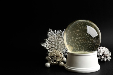 Photo of Beautiful empty snow globe and Christmas decor on black background, space for text
