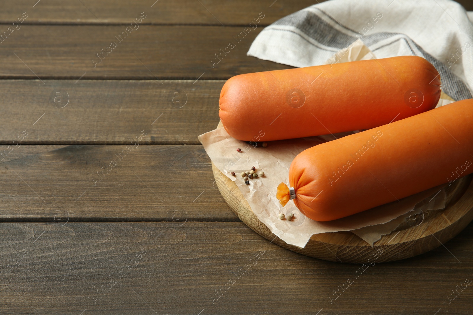 Photo of Board with tasty boiled sausages on wooden table. Space for text