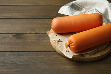 Photo of Board with tasty boiled sausages on wooden table. Space for text