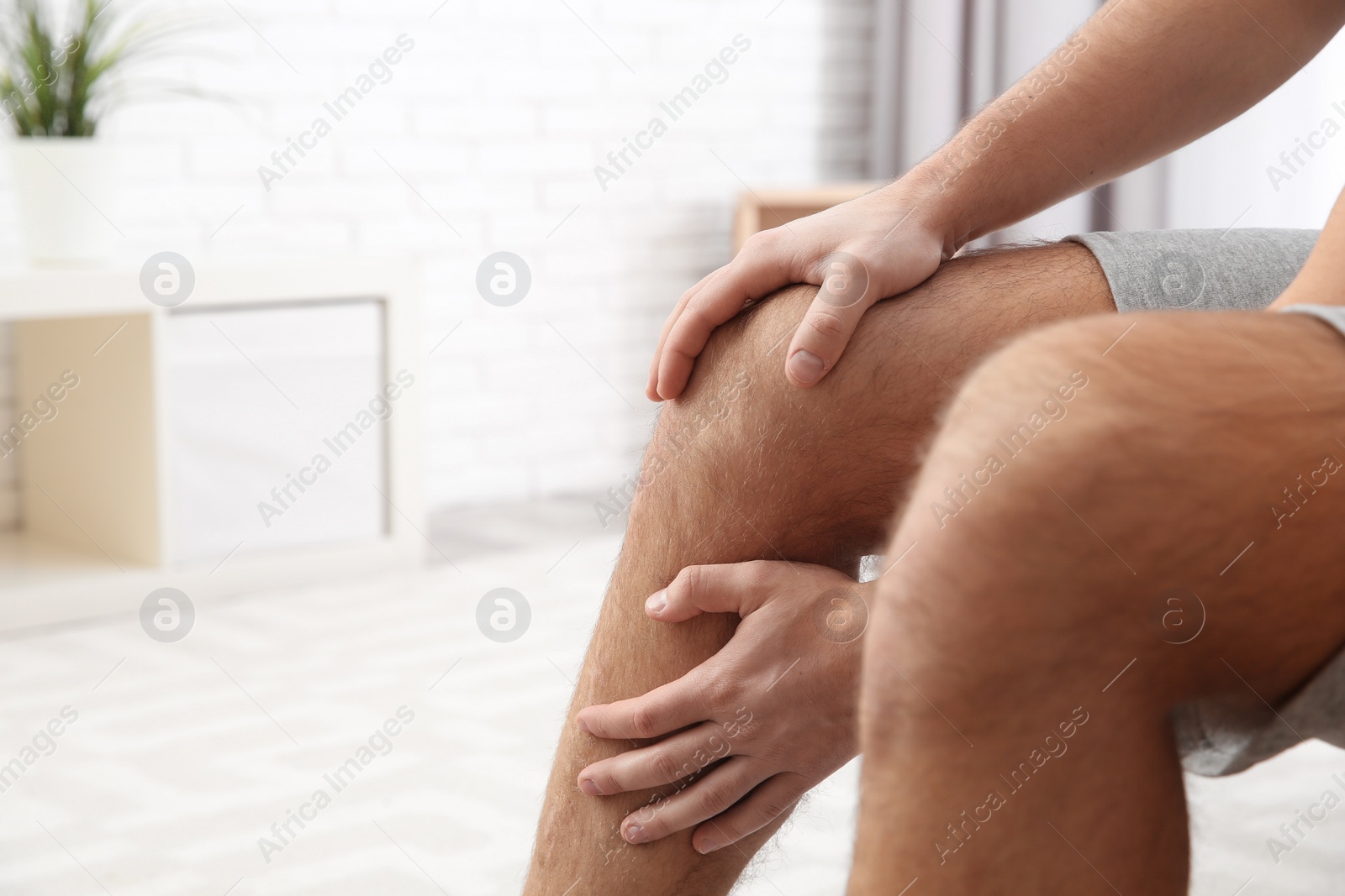 Photo of Man suffering from leg pain at home, closeup. Space for text