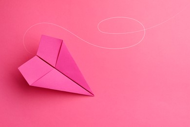 Image of Handmade paper plane on pink background, top view. Space for text