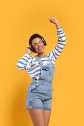 Photo of Happy young woman dancing on orange background