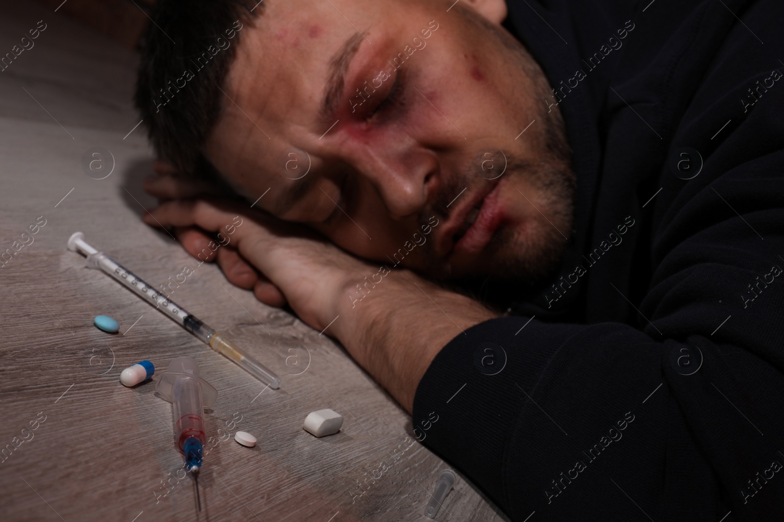 Photo of Overdosed man indoors, focus on different drugs