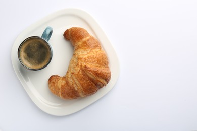 Delicious fresh croissant and cup of coffee on white background, top view. Space for text