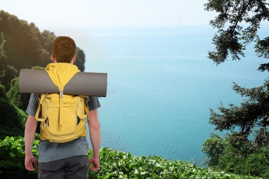 Tourist with backpack on hill over sea, back view
