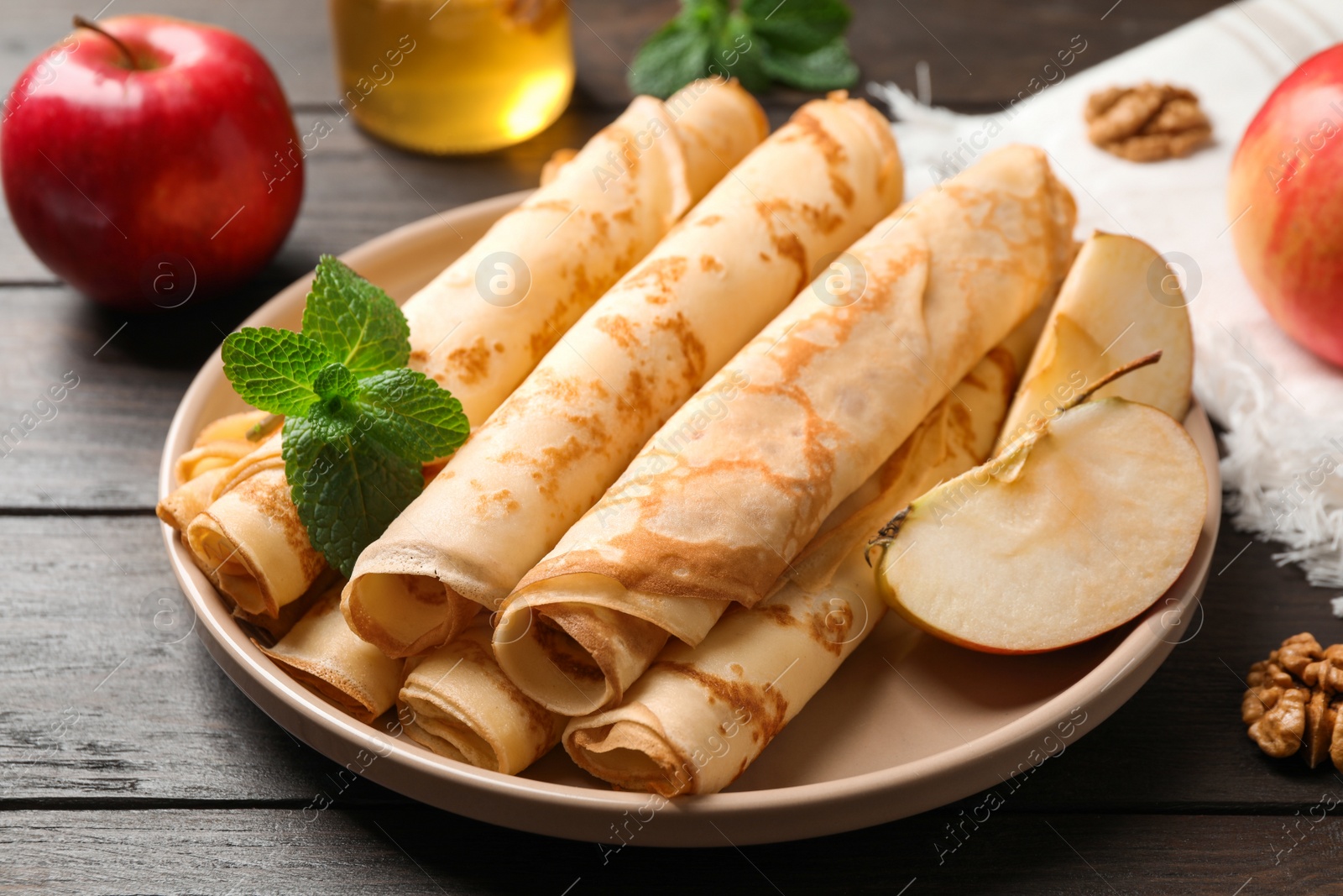 Photo of Delicious rolled thin pancakes on wooden table