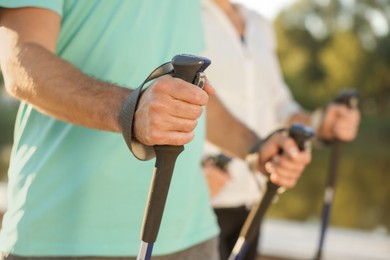 Man practicing Nordic walking with poles outdoors, closeup