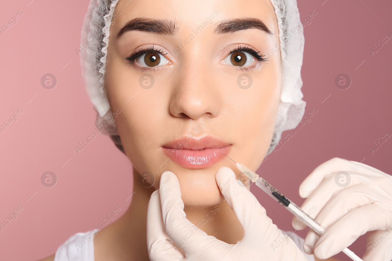 Photo of Young woman getting lip injection on color background