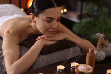 Photo of Spa therapy. Beautiful young woman lying on massage table in salon