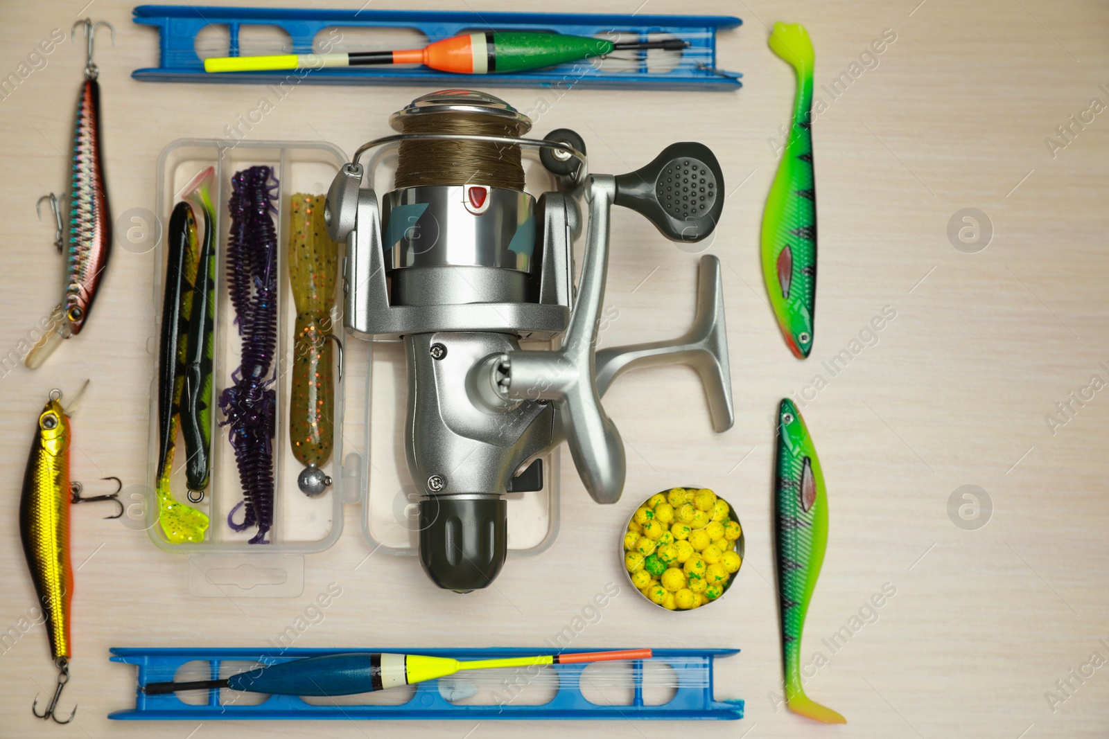 Photo of Different fishing equipment on light wooden table, flat lay