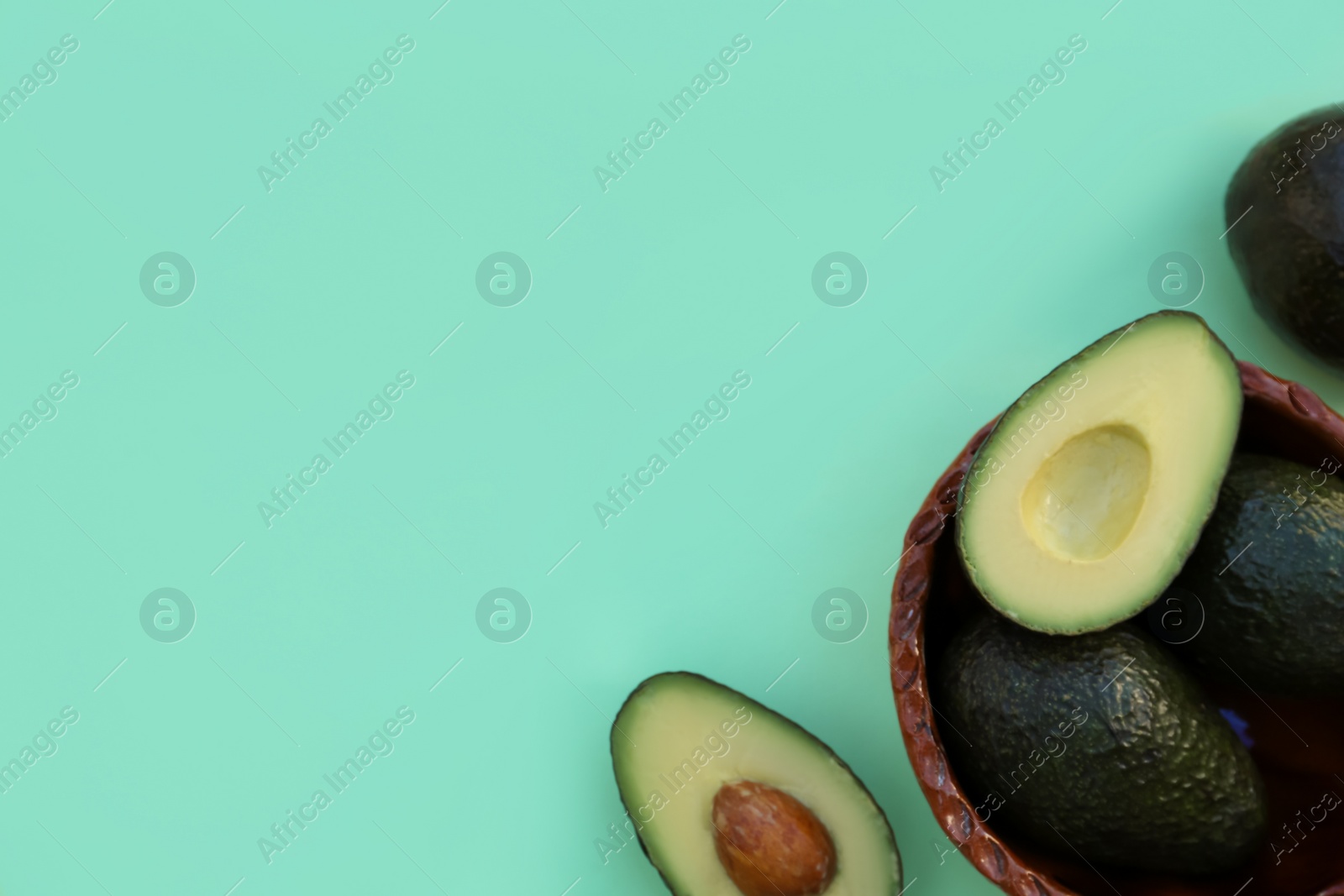 Photo of Tasty fresh avocados on turquoise background, flat lay. Space for text