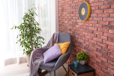 Photo of Stylish room interior with armchair and potted ficus