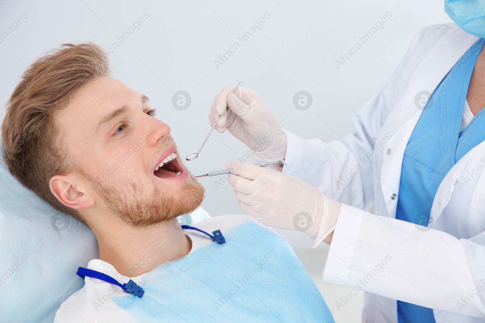 Photo of Dentist examining patient's teeth in modern clinic