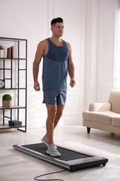 Sporty man training on walking treadmill at home