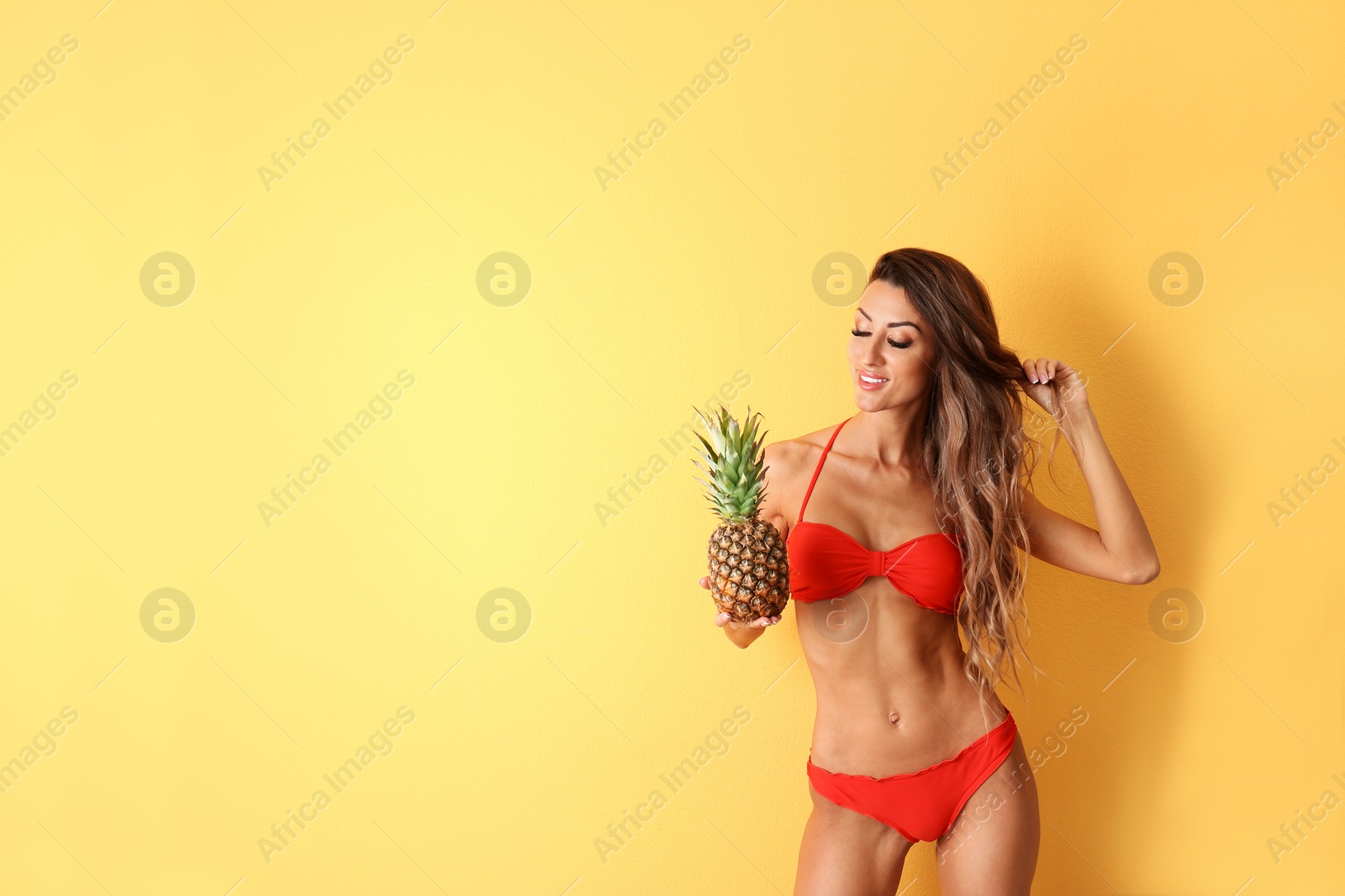 Photo of Pretty sexy woman in stylish bikini with pineapple on color background, space for text