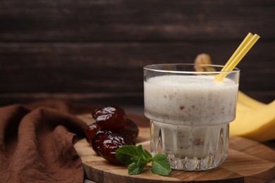 Glass of delicious date smoothie, mint and dried fruits on wooden board. Space for text