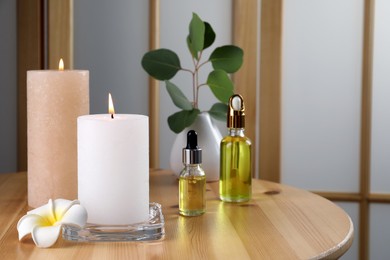 Photo of Burning candles, essential oil and plumeria flower on wooden table