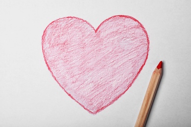 Photo of Drawn heart and pencil on sheet of paper, top view