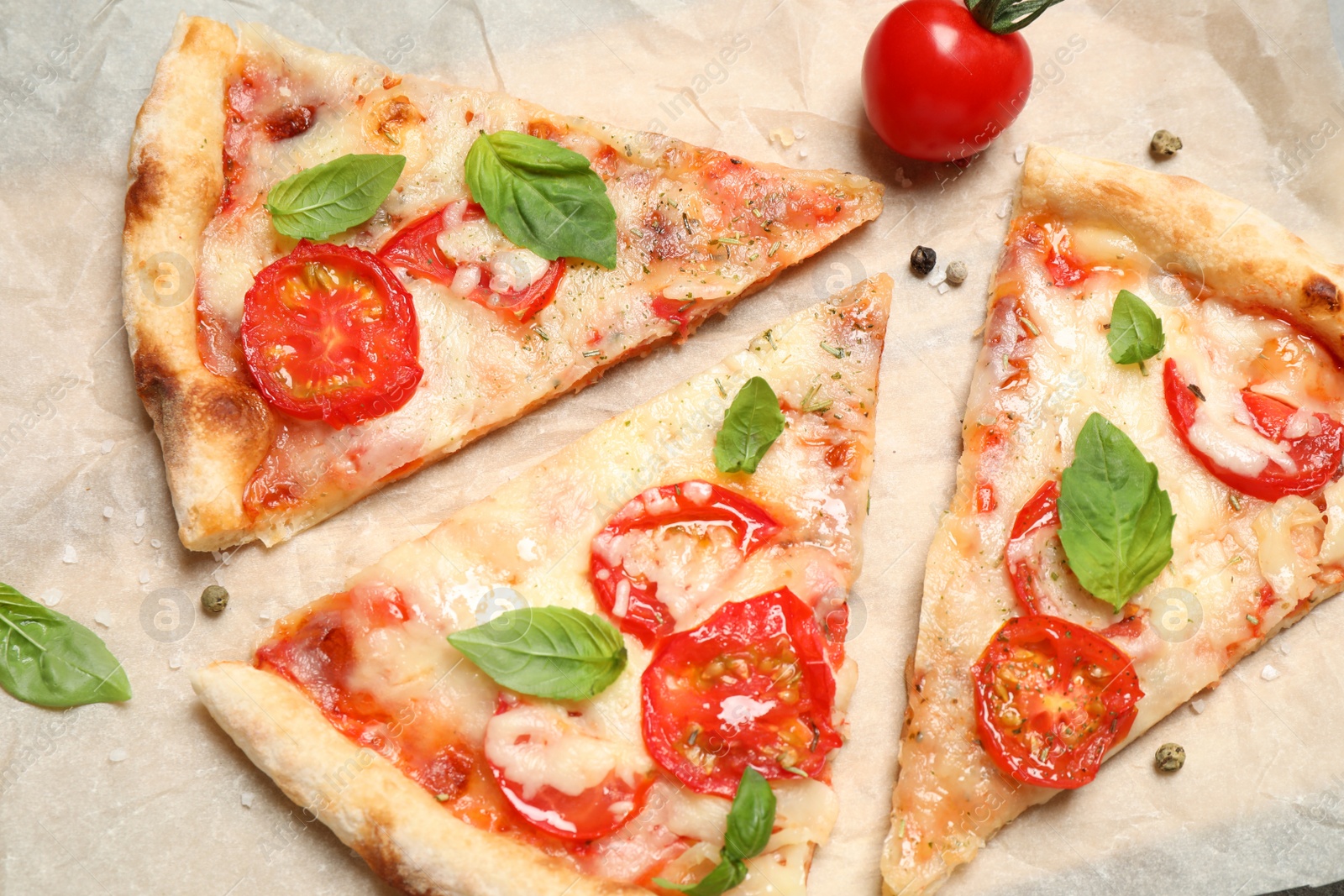 Photo of Slices of delicious pizza Margherita on parchment, flat lay