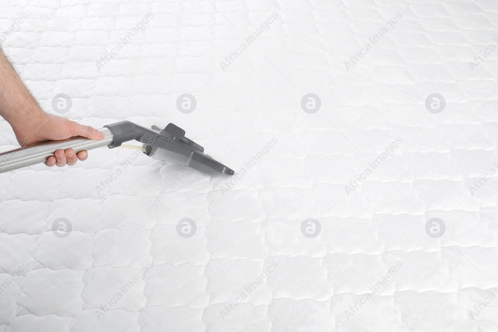 Photo of Man disinfecting mattress with vacuum cleaner, closeup. Space for text