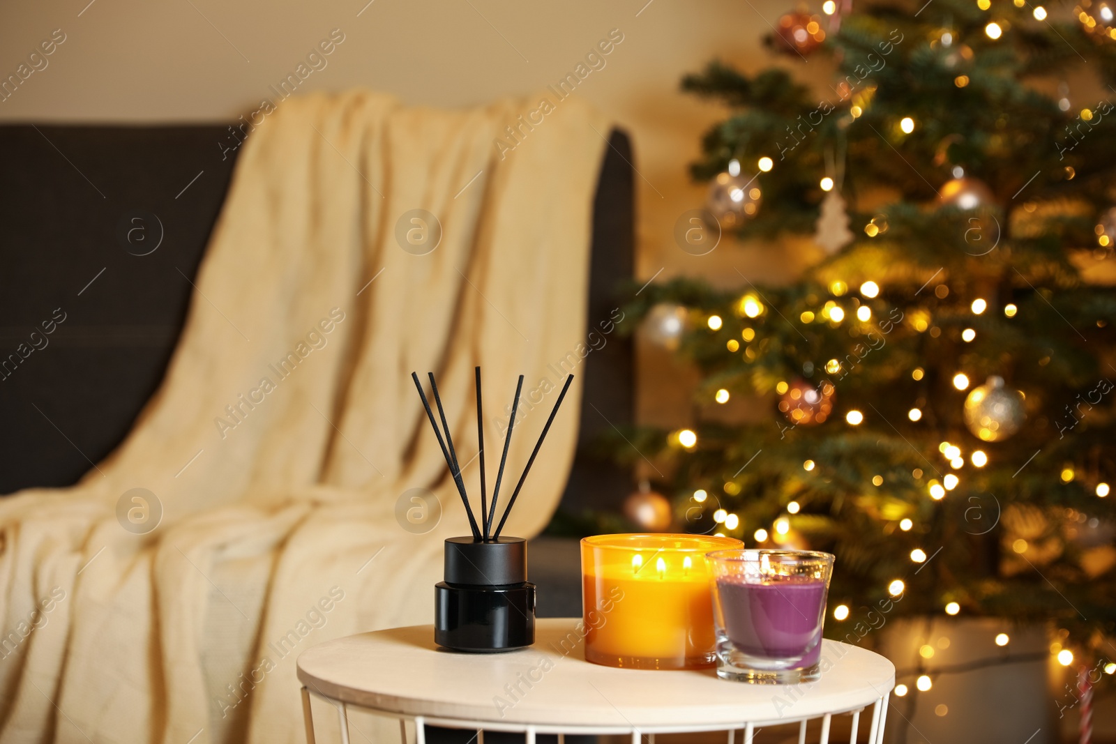 Photo of Beautiful candles and reed air freshener near Christmas tree indoors. Cosy atmosphere