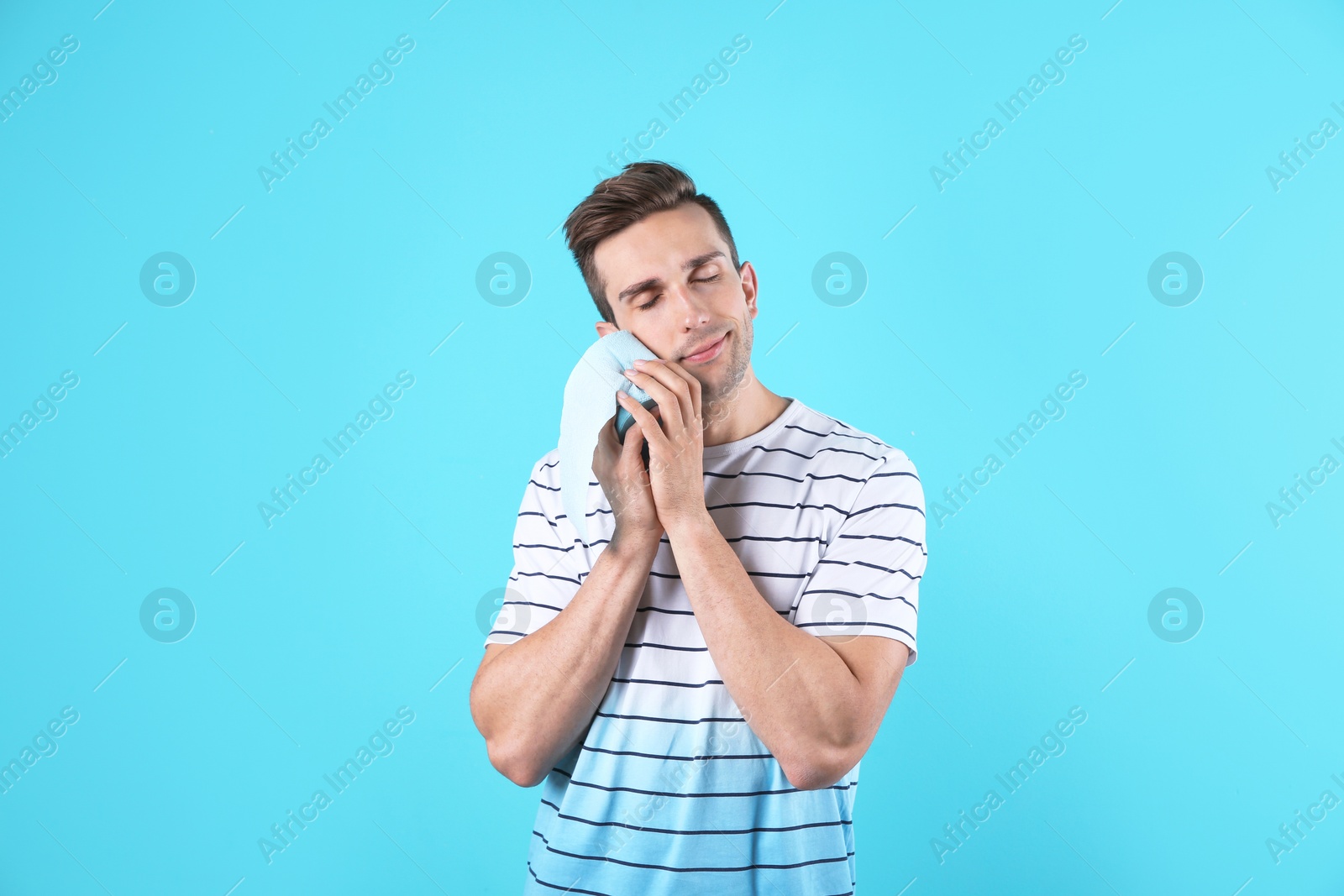 Photo of Young man holding toilet paper roll on color background