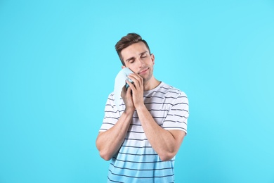 Young man holding toilet paper roll on color background