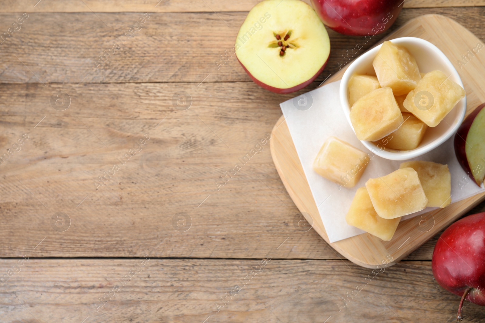 Photo of Frozen apple puree cubes and ingredient on wooden table, flat lay. Space for text