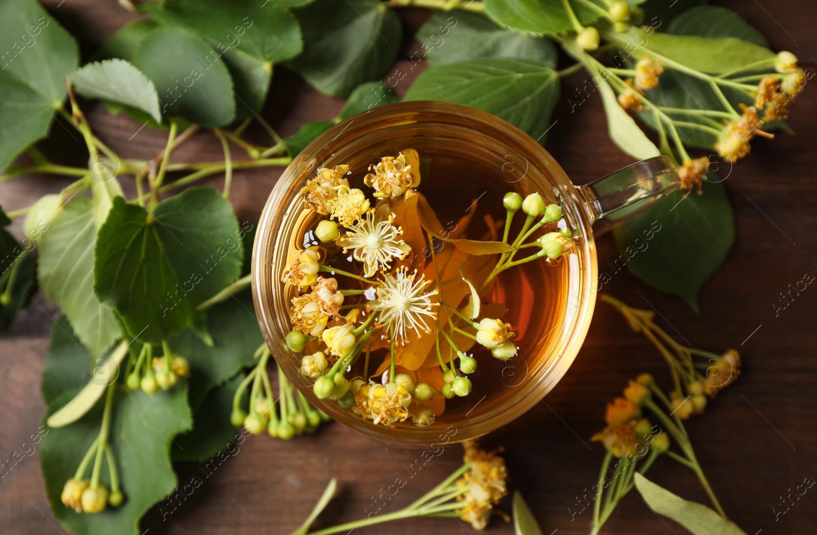 Photo of Cup of tea and linden blossom on wooden table, flat lay