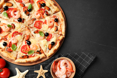 Photo of Tasty pizza with seafood and ingredients on black table, flat lay