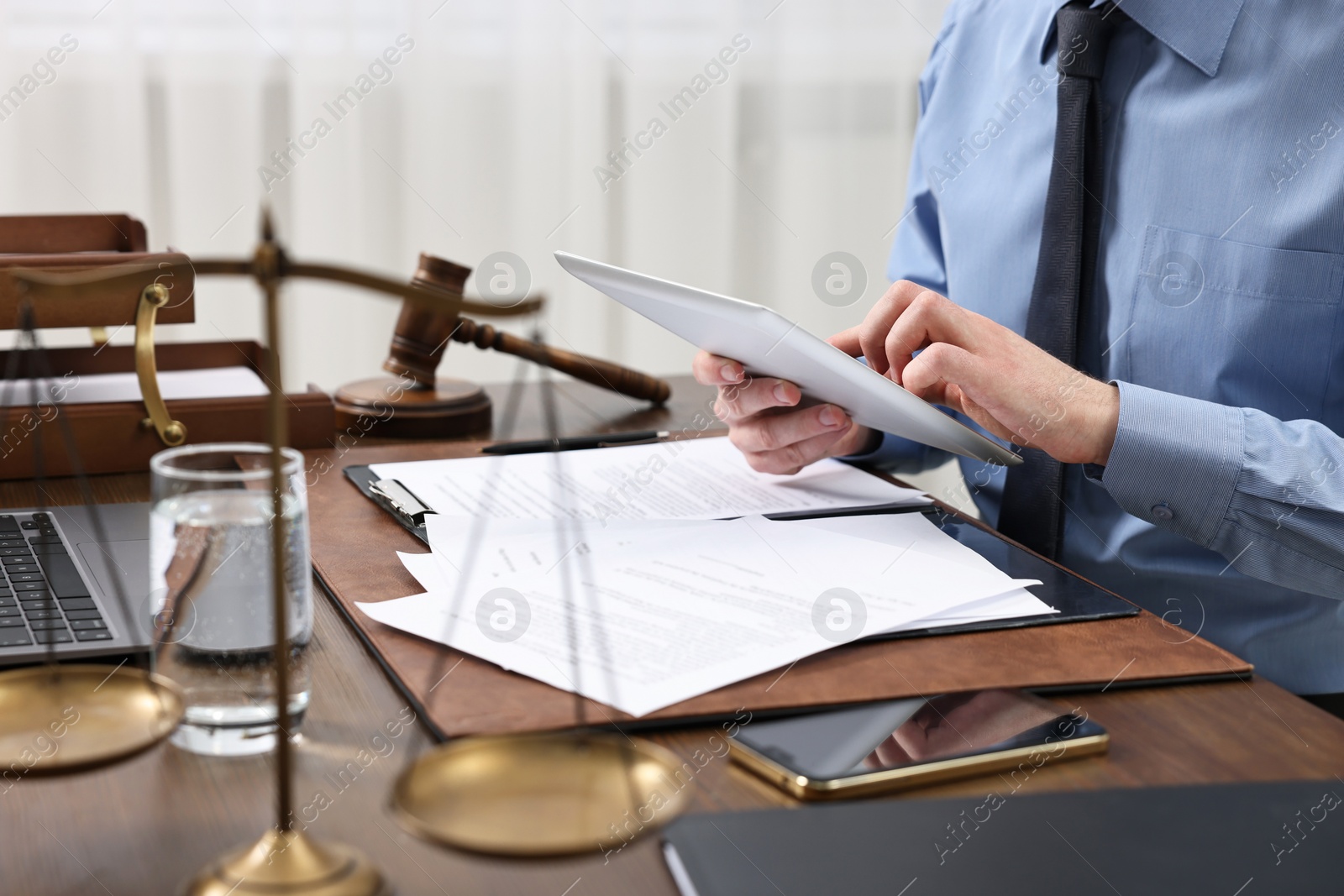 Photo of Lawyer using tablet at wooden table, closeup