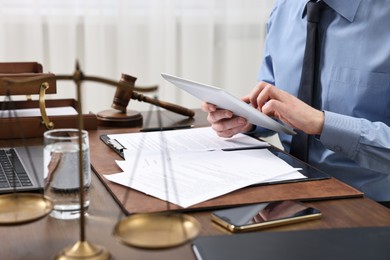 Photo of Lawyer using tablet at wooden table, closeup