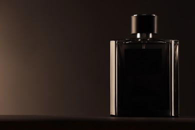 Photo of Luxury men`s perfume in bottle on table against dark background, space for text