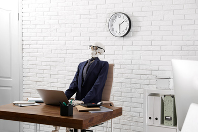 Photo of Human skeleton in suit using laptop at table in office