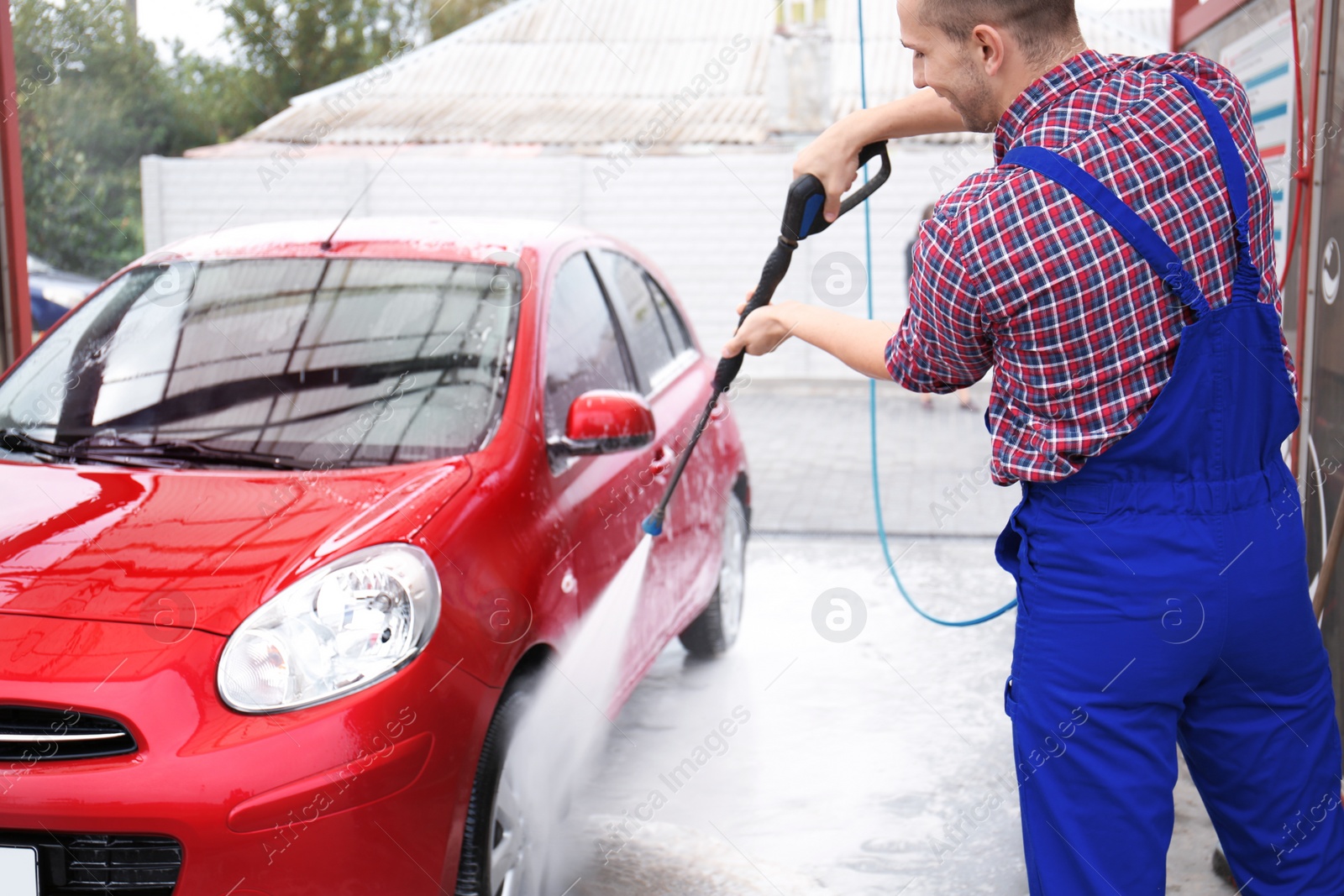 Photo of Male worker cleaning vehicle with high pressure water jet at car wash