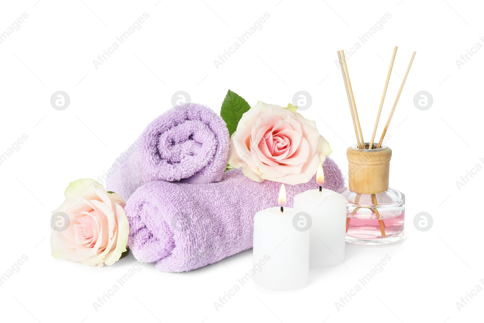 Photo of Spa composition. Towels, burning candles, reed air freshener and rose flowers on white background