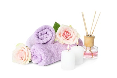 Photo of Spa composition. Towels, burning candles, reed air freshener and rose flowers on white background