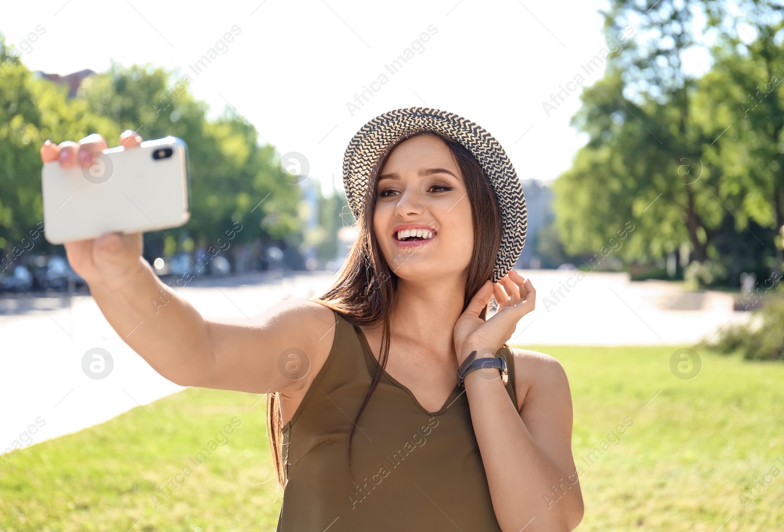 Photo of Young woman taking selfie outdoors on sunny day