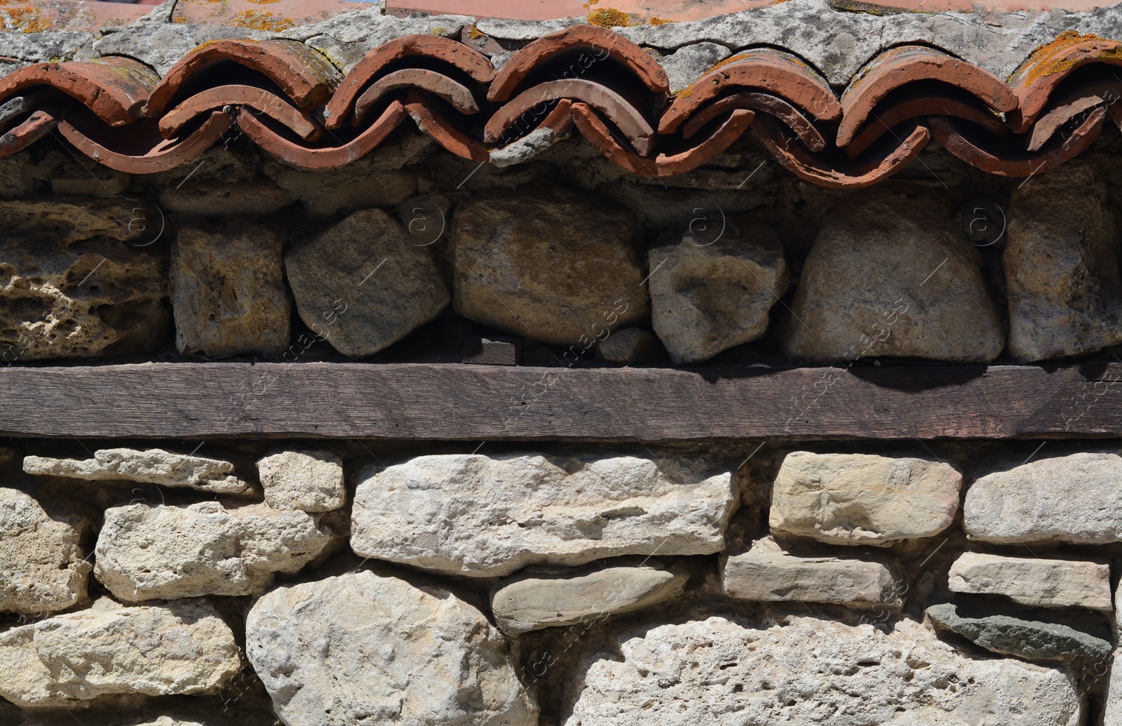 Photo of Old stone wall with ceramic tiles roof on sunny day