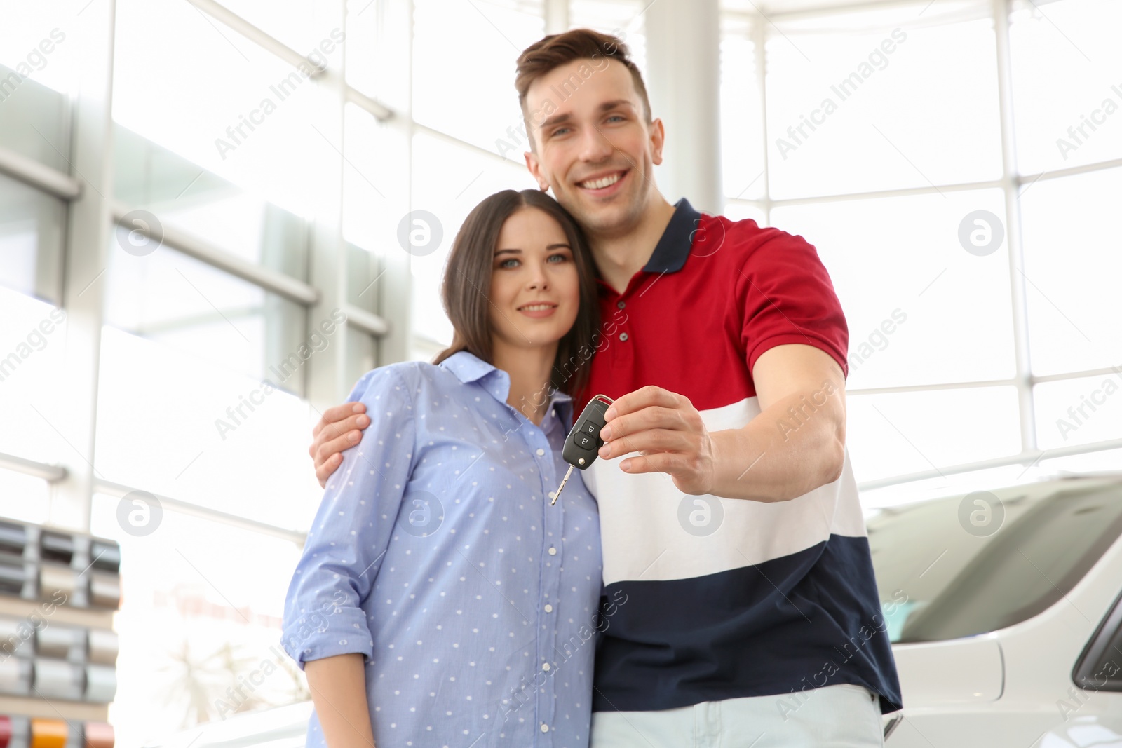 Photo of Young couple with key in salon. Buying new car