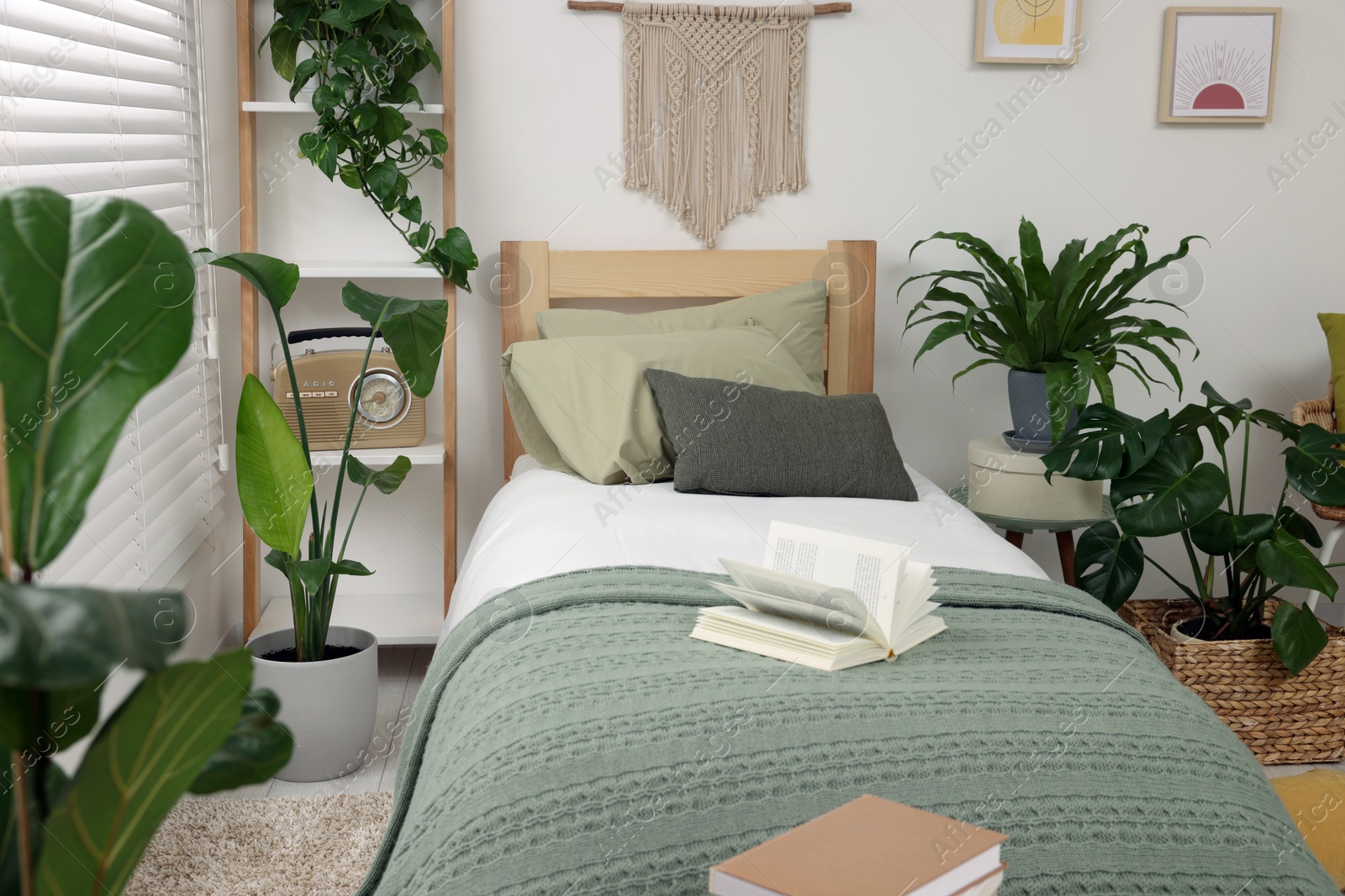 Photo of Large comfortable bed and potted houseplants in stylish bedroom. Interior design