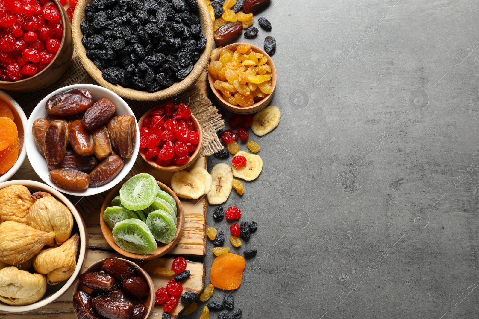 Photo of Bowls of different dried fruits on grey background, top view with space for text. Healthy food